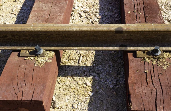 Close up bolted butt of rails and wooden sleepers laid on groundwork crushed stone. Railway industry and transport infrastructure — Stock Photo, Image