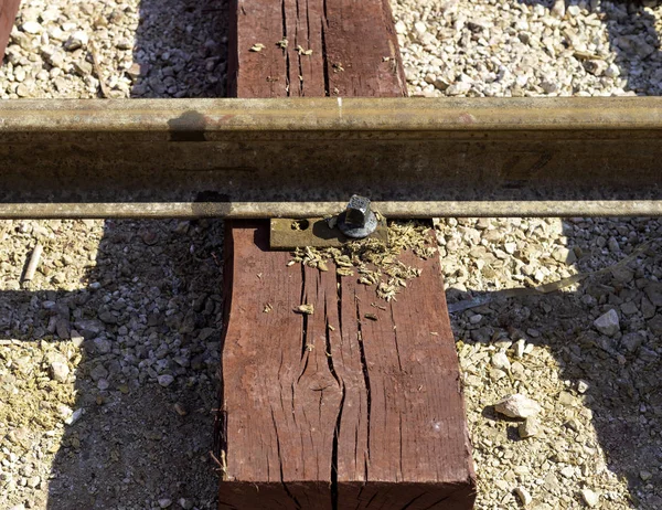 Close up bolted butt of rails and wooden sleepers laid on groundwork crushed stone. Railway industry and transport infrastructure — Stock Photo, Image