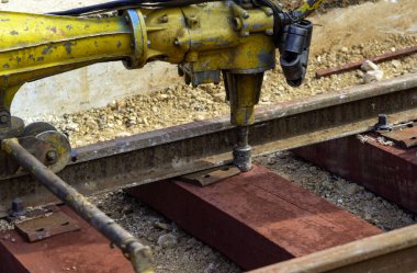 Rayları sürgüleyen demiryolu işçileri. Mekanik cıvata anahtarı olan detaycı işçi