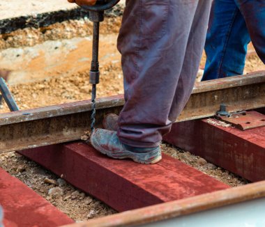 Rayları sürgüleyen demiryolu işçileri. Hafif portatif sondaj makinesi olan detaycı.