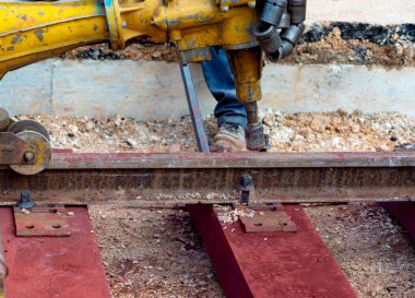 Rayları sürgüleyen demiryolu işçileri. Hafif portatif sondaj makinesi olan detaycı.