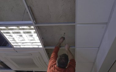 İşçi alçıtaşıyla tahta tavanı onarıyor. Sınıfta.