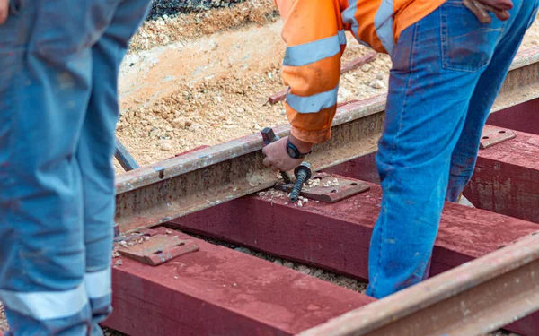 Railway workers bolting track rail. Detail worker with mechanical bolting wrench