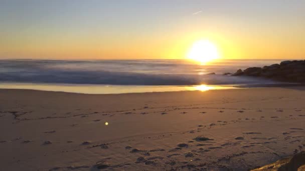 Atardecer timelapse con olas chocan en la orilla en una playa de arena — Vídeos de Stock