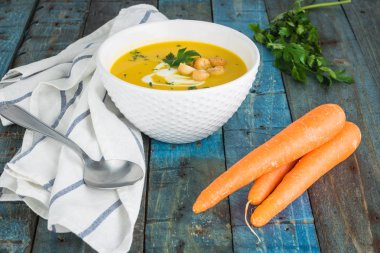 Krem ve ahşap zemin üzerine maydanoz ile havuç çorbası