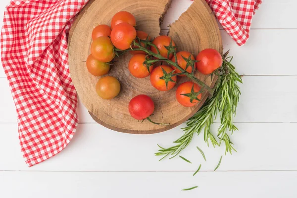Organic cherry tomatoes with rosemary on rustic wooden table — Stock Photo, Image