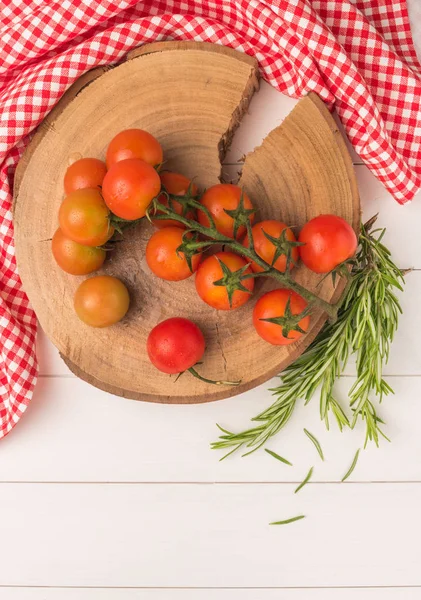 Organic cherry tomatoes with rosemary on rustic wooden table — Stock Photo, Image