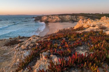 Alentejo, Portekiz 'de Porto Covo' da kayalıklarla plajda gün batımı
