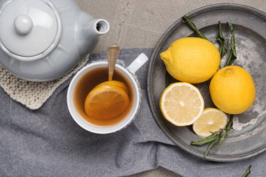 Tablo yakın çekim üzerinde limonlu çay fincan. Sağlık geleneksel tıp ve grip kavramı - limon ile çay bardağı. Sıcak çay limon tedavi soğuk algınlığı grip ve akıntısı ile.