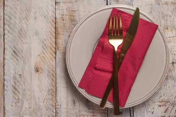 Table setting with plate golden fork and knife on wooden background — Stock Photo, Image