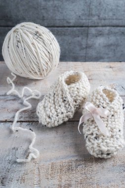 Ahşap masa üzerinde bege iplik ile bebek patiği örgü