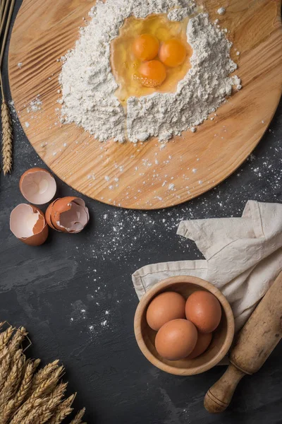 Top view eggs, dough, flour and rolling-pin on wooden table — Stock Photo, Image