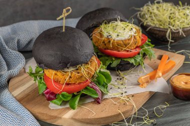 Lezzetli ızgara vejetaryen burger, nohut ve ahşap arka planda siyah ekmek üzerine sebze.