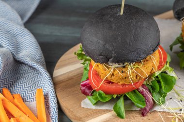 Lezzetli ızgara vejetaryen burger, nohut ve ahşap arka planda siyah ekmek üzerine sebze.