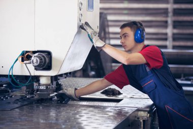 Bir fabrika içinde eylem Metal Sanayi işçisi basın makine çelik parça çalışılacak hazır tutuyor.