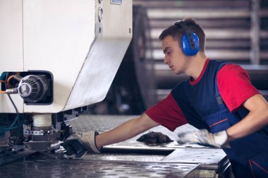Bir fabrika içinde eylem Metal Sanayi işçisi basın makine çelik parça çalışılacak hazır tutuyor.