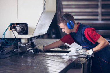 Bir fabrika içinde eylem Metal Sanayi işçisi basın makine çelik parça çalışılacak hazır tutuyor.