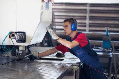 Bir fabrika içinde eylem Metal Sanayi işçisi basın makine çelik parça çalışılacak hazır tutuyor.