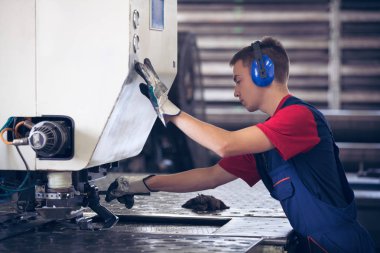 Bir fabrika içinde eylem Metal Sanayi işçisi basın makine çelik parça çalışılacak hazır tutuyor.