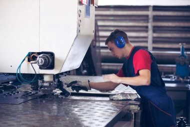 Bir fabrika içinde eylem Metal Sanayi işçisi basın makine çelik parça çalışılacak hazır tutuyor.