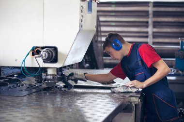Bir fabrika içinde eylem Metal Sanayi işçisi basın makine çelik parça çalışılacak hazır tutuyor.