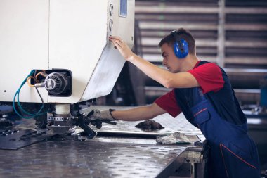 Bir fabrika içinde eylem Metal Sanayi işçisi basın makine çelik parça çalışılacak hazır tutuyor.