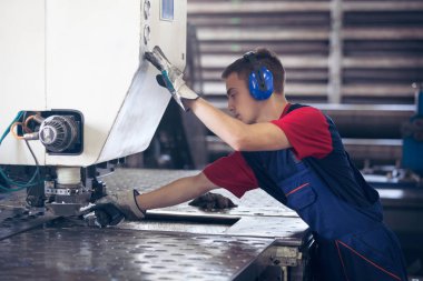 Bir fabrika içinde eylem Metal Sanayi işçisi basın makine çelik parça çalışılacak hazır tutuyor.