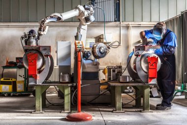İşçi metal parçalar robotized kolu ile kaynak için hazırlar.