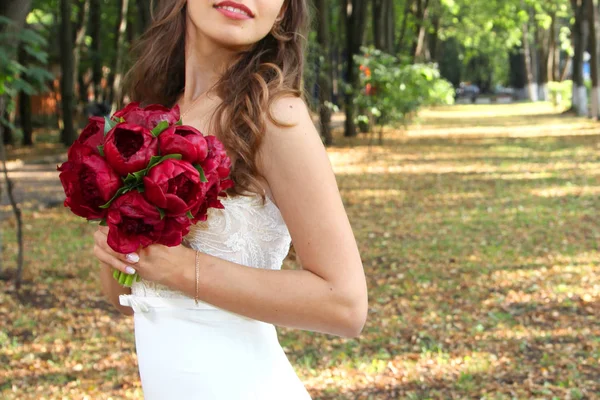 Wedding bouquet of red roses in the hands of the bride — Stock Photo, Image