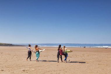 Croyde Körfezi Kuzey Devon İngiltere'de kadın sörfçü sahilde
