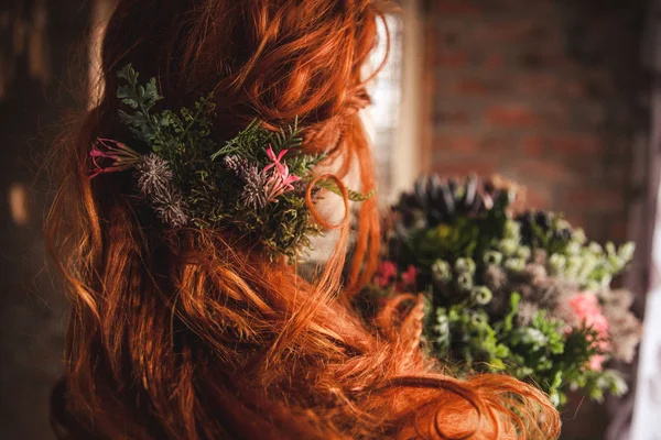 bride with red hair with flowers in her hands and hair