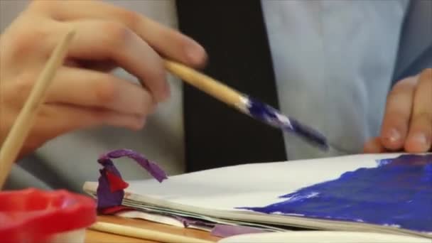 Child paints with a brush and gouache on paper — Stock Video