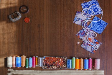 Bir dikiş ve iğne işi için ayarlayın. Renkli konu, boncuk, kumaş parçaları ve ahşap masa üzerinde ZIP