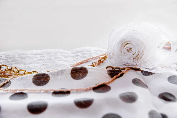 En rulle vit spets och en kostymkedja på ett prickigt tyg på nära håll. — Stockfoto
