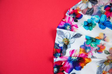 Parlak pembe arka planda kumaşlı, çok renkli çiçekli beyaz bir kumaş parçası. Mesaj için yer var. Tasarım konsepti