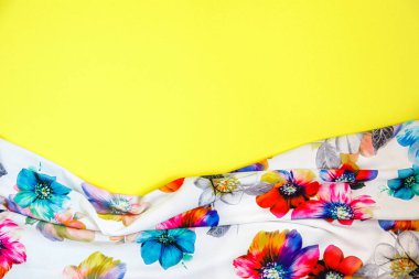 Parlak sarı arka planda kumaşlı, çok renkli çiçekleri olan beyaz bir kumaş parçası. Mesaj için yer var. Tasarım konsepti
