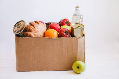Beyaz arka planda gıda bağışı olan karton bir kutu. Yoksullara yardım
