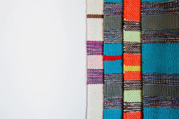 Несколько ярко окрашенных полосатых текстильных ковриков на белом фоне. Цветная текстильная текстура с пространством для текста — стоковое фото