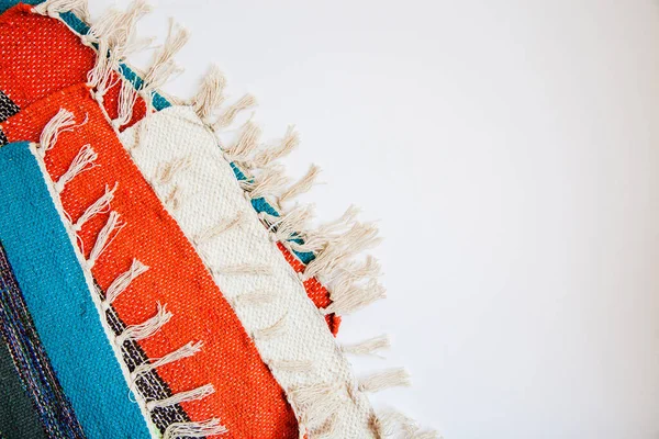 Несколько ярко окрашенных полосатых тканевых ковриков с кисточками на белом фоне. Цветная текстильная текстура с пространством для текста — стоковое фото