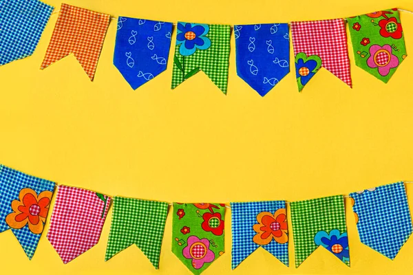 Multicolored fabric flags on a yellow background. Decorations for the holiday. Flat layout with space for text