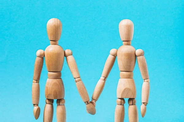 Relationship between people. Two wooden mannequins hold hands