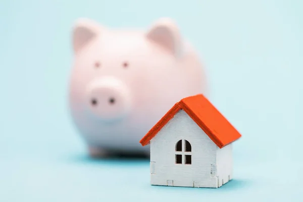 Toy house and piggy bank on a blue background. The concept of saving money for your home
