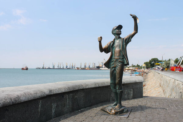  Бердянск, Украина - 19 июля 2018 года: Памятник молодому рыбаку с Азовским круглым прохожим в Бердянске
