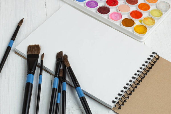 Кисти для рисования и пустой альбом эскизов
