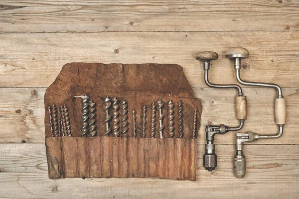 Braçadeiras de broca com pedaços em rolo de ferramentas de couro em uma bancada de madeira — Fotografia de Stock