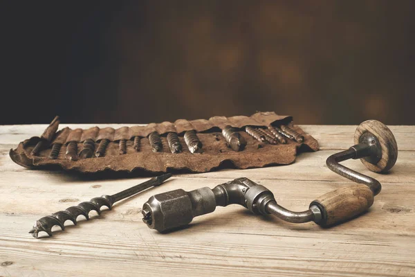 Drill brace with bits in leather tool roll on a wooden workbench — Stock Photo, Image