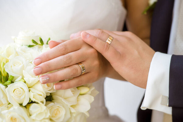 close-up of male and female hands holding beautiful wedding bouquet of white flowers 