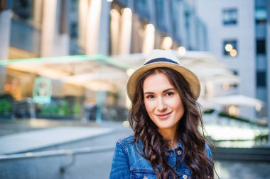 Kot ceket ve şehir yürüyüş sırasında poz şapka genç kadın