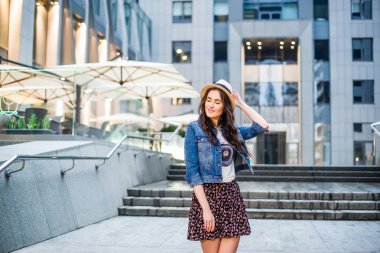 Kot ceket ve şehir yürüyüş sırasında poz şapka genç kadın