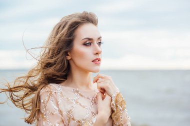 genç güzel kadın gelinlikle deniz kıyısında günbatımı poz 